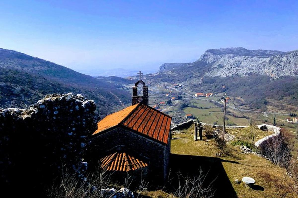 ένα μικρό κτίριο στην κορυφή ενός λόφου με βουνά στο φόντο