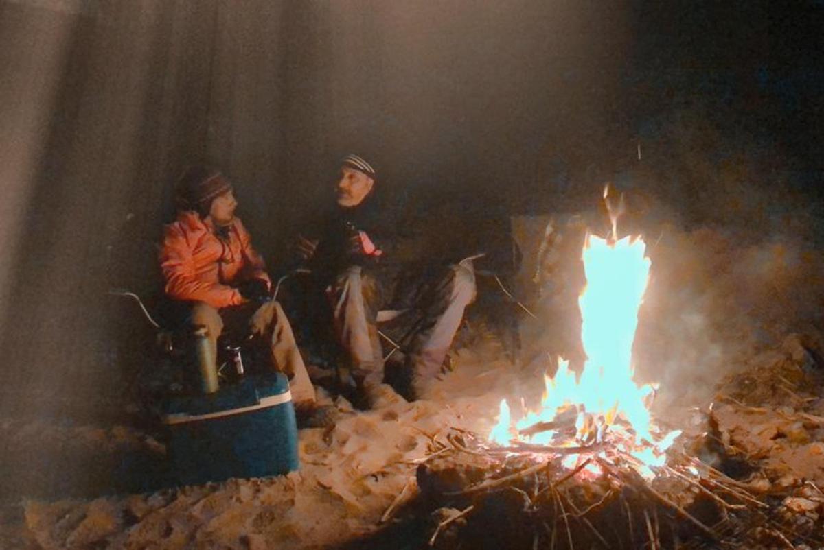 a group of three people sitting around a fire