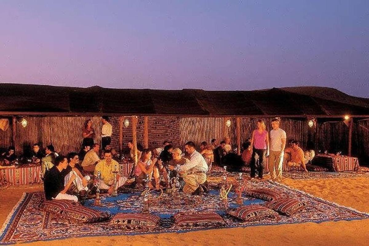 büyük bir halının etrafında oturan bir grup insan