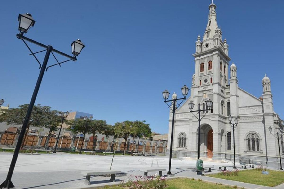 Una iglesia con una torre con un banco delante de ella.