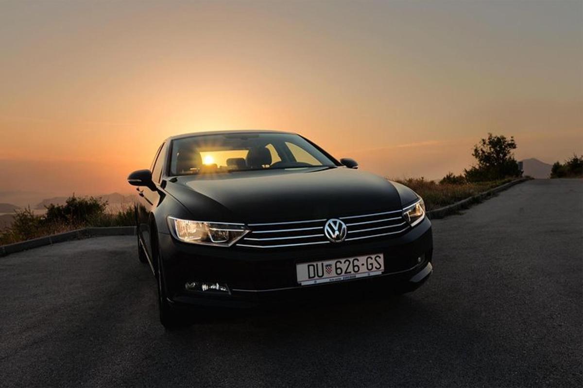 černé auto zaparkované na silnici se západem slunce v pozadí