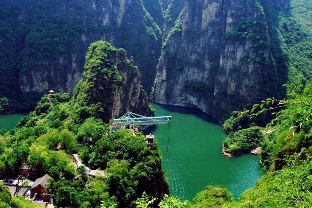 a river with a bridge in the middle of a mountain