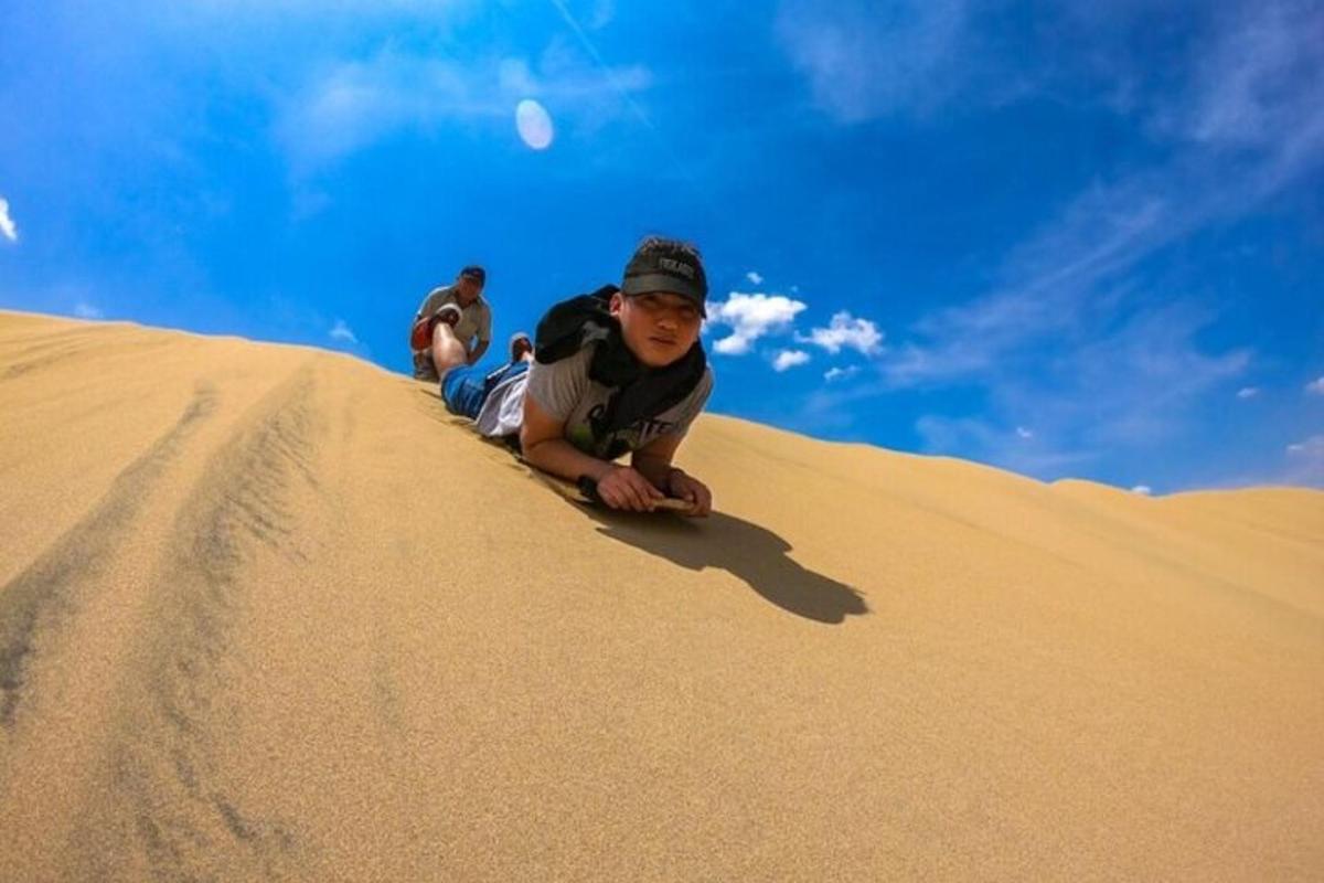 a young boy laying on top of a sand hill