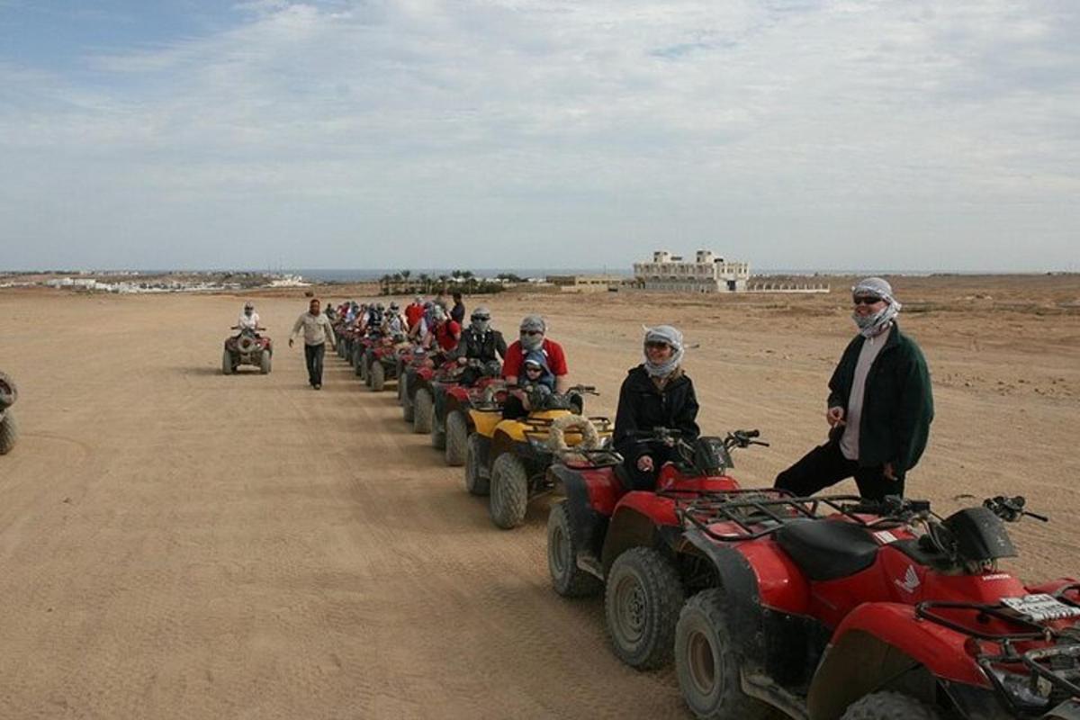 a group of people standing around atvs in the desert