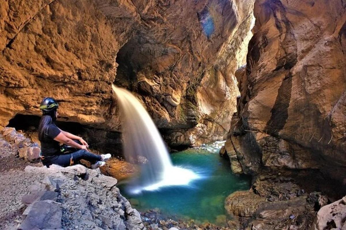 ein Mann sitzt auf einem Felsen neben einem Wasserfall