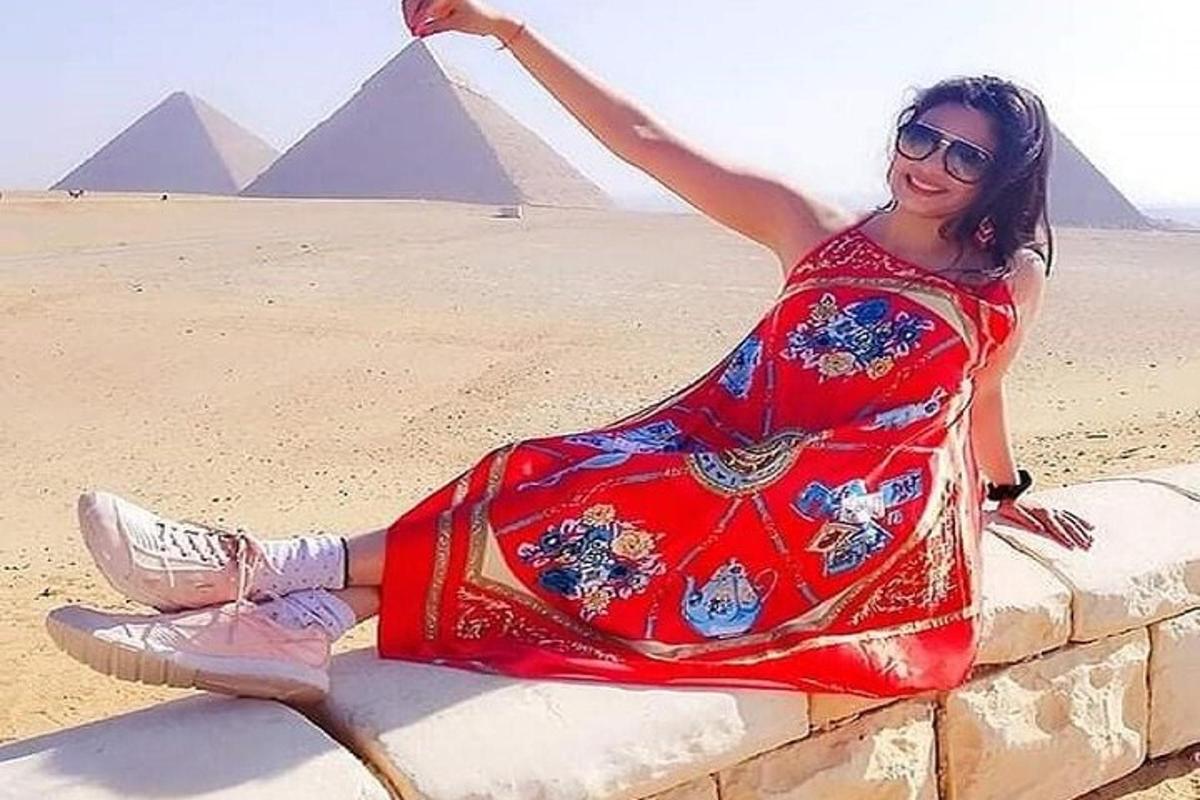 a woman sitting on a wall in front of the pyramids
