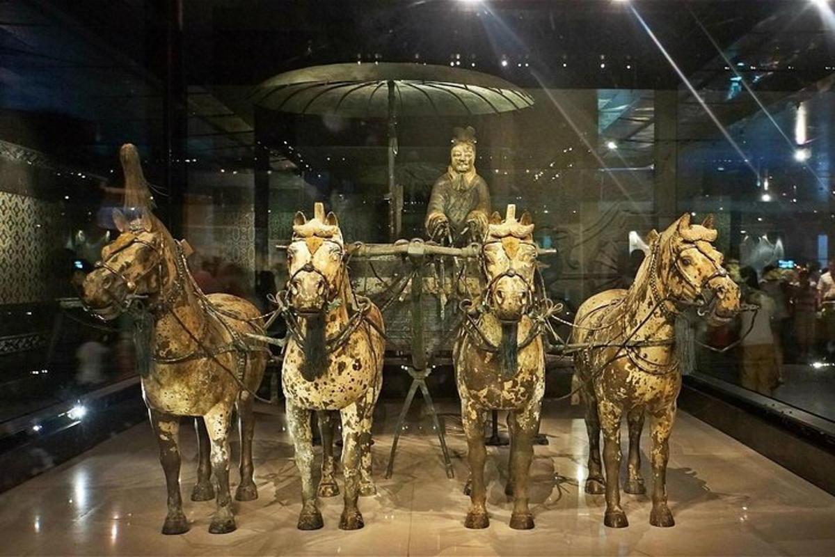 a group of horses pulling a cart with a statue