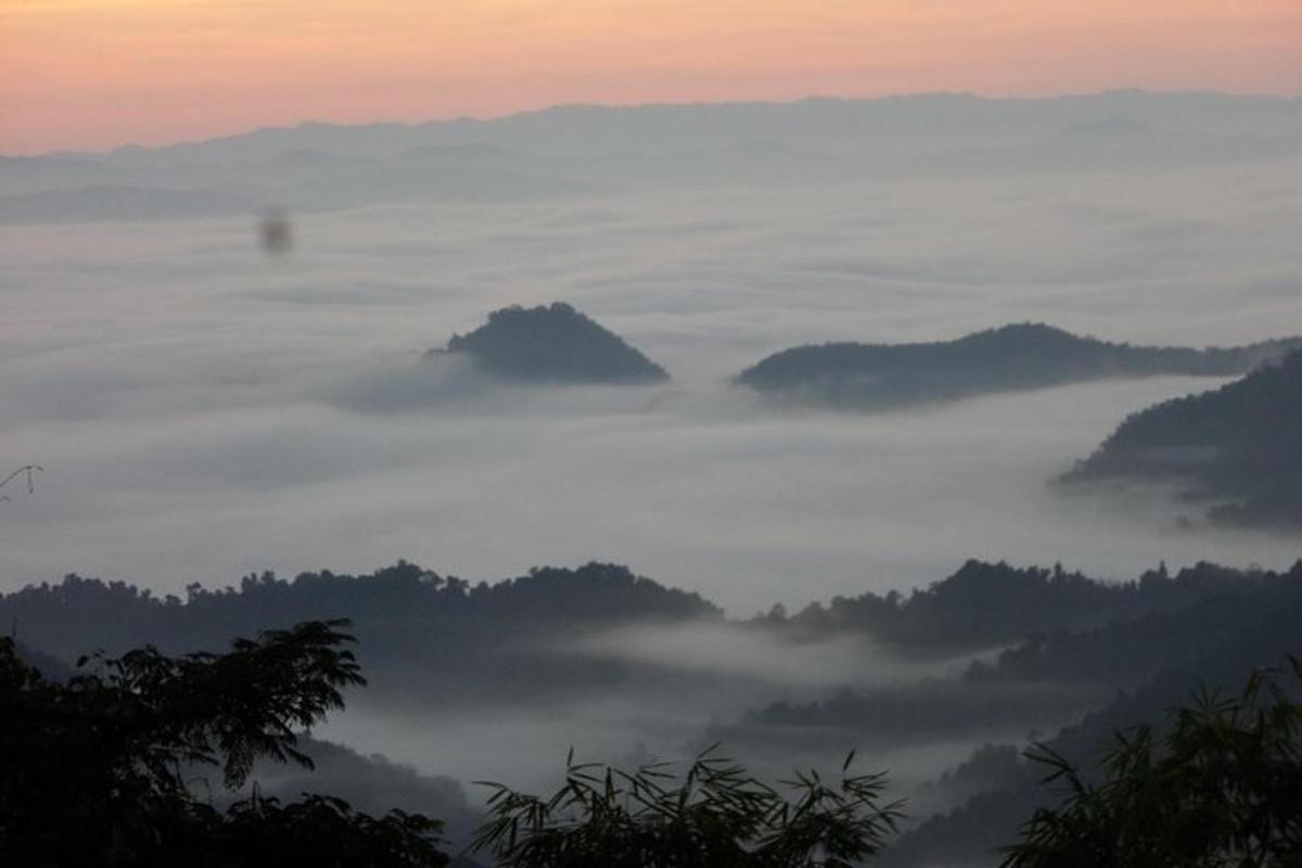 a view of a foggy valley with mountains in the background