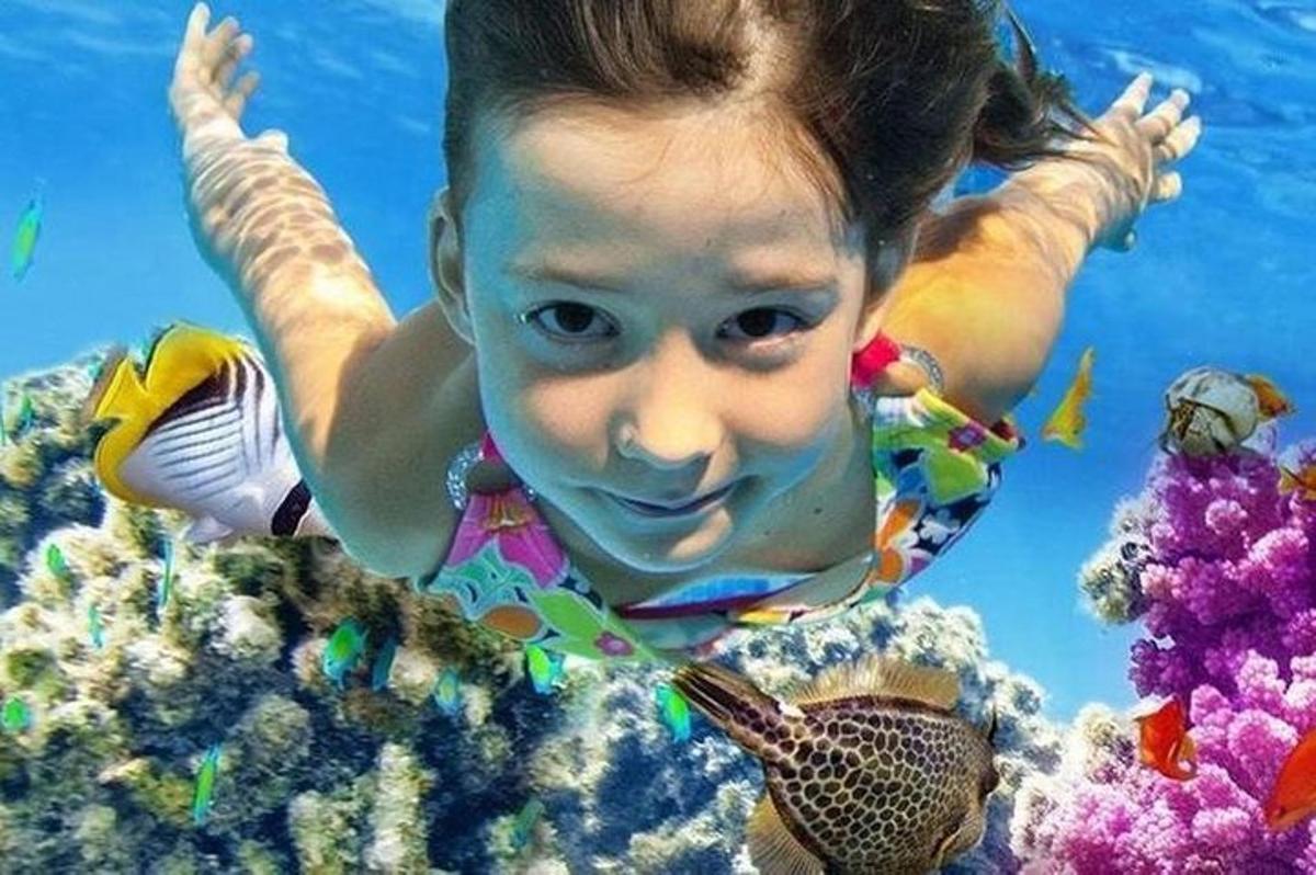 una bambina che nuota nell'acqua con un pesce
