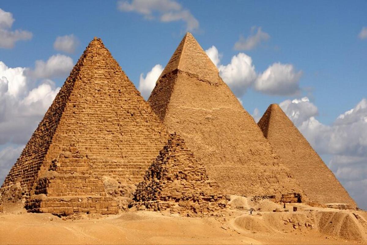 um grupo de pirâmides no deserto com céu nublado