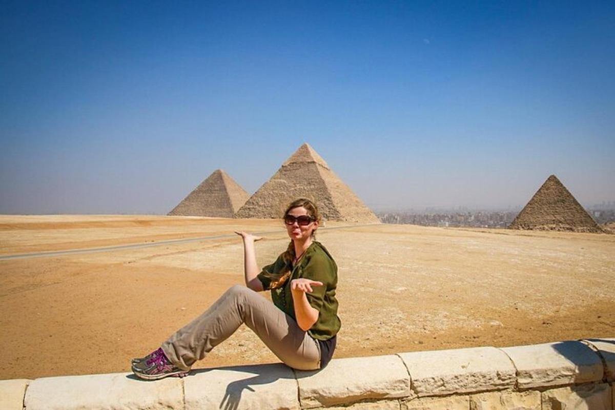 una donna seduta su un muro di fronte alle piramidi