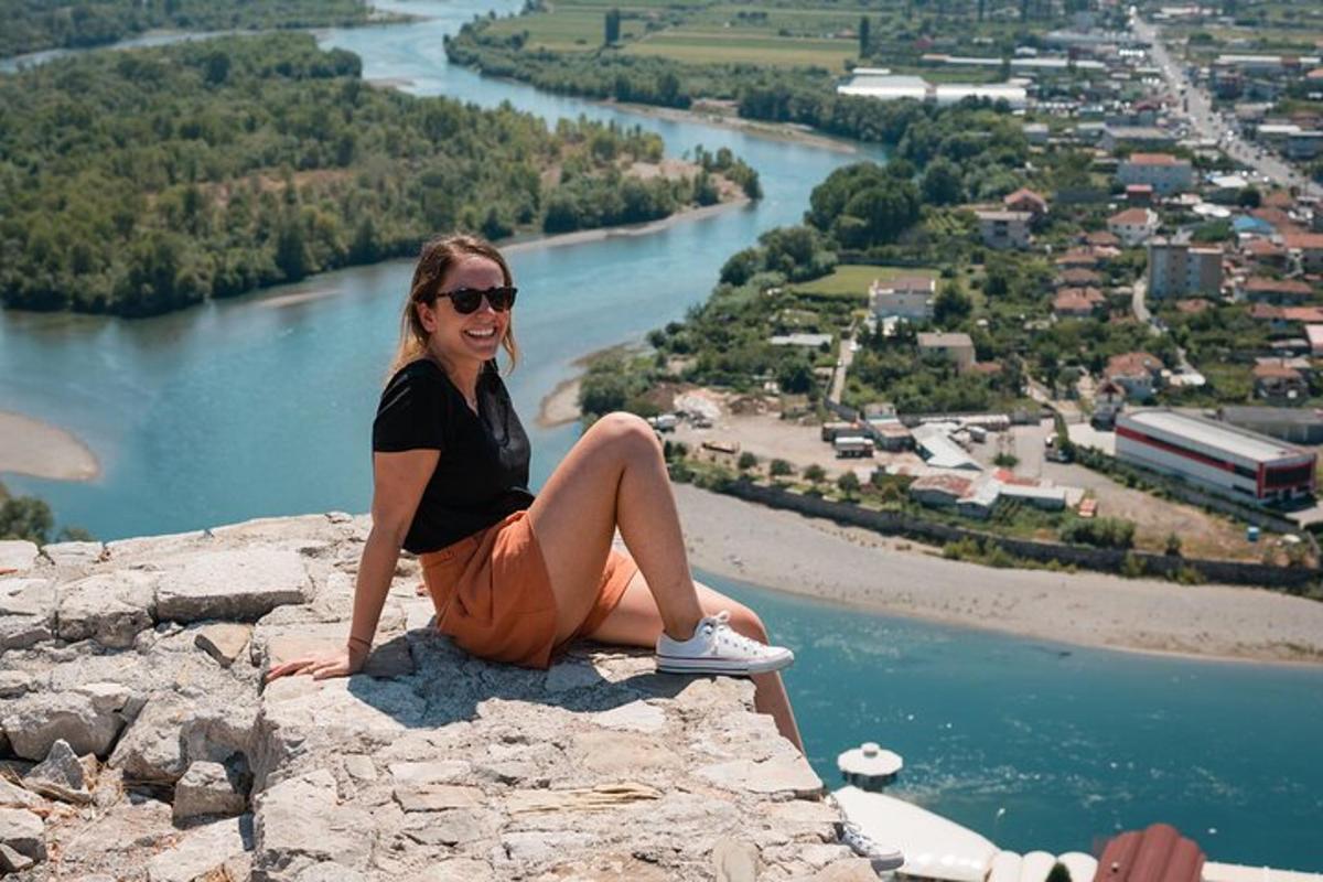 una dona asseguda a la vora d'una roca amb vistes a un riu