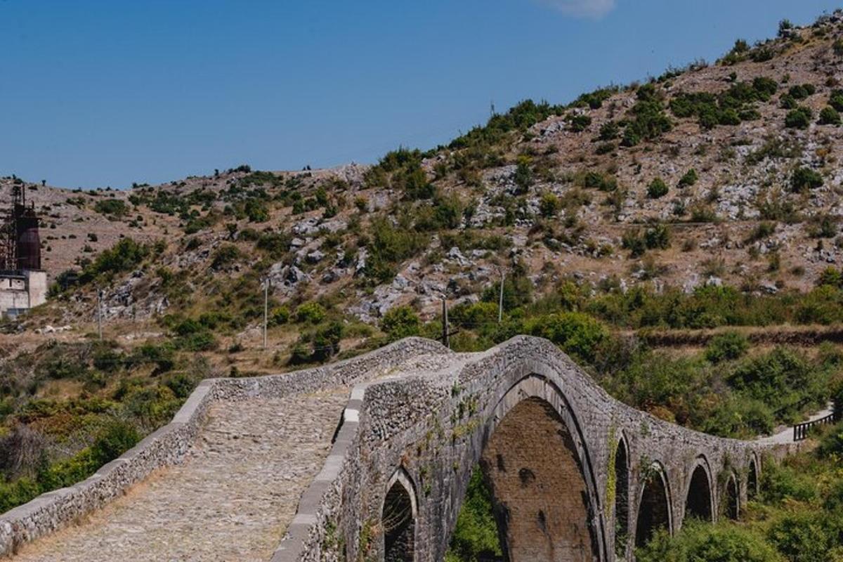 un pont de pedra sobre un turó amb una muntanya