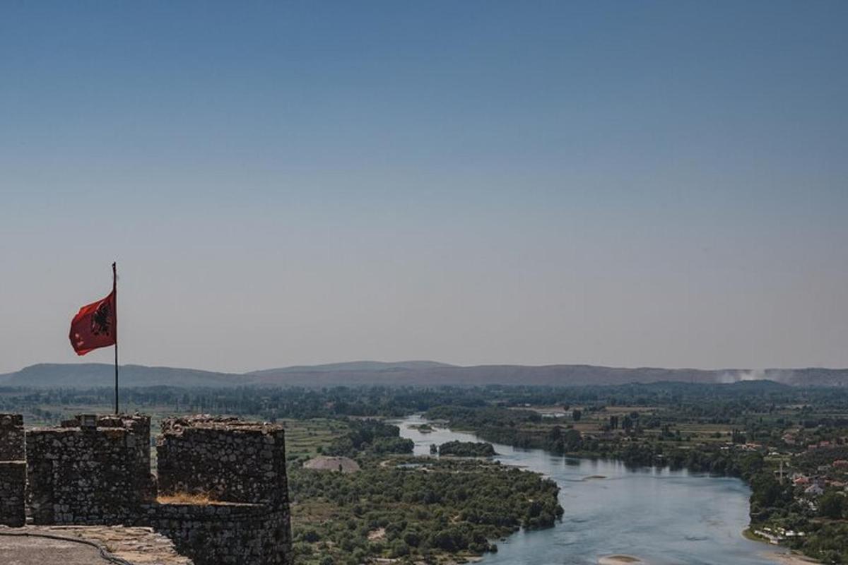 una bandera a dalt d'un castell al costat d'un riu