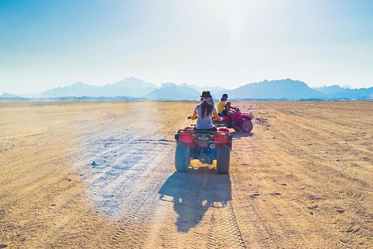 due persone in sella a un quad su un campo sterrato