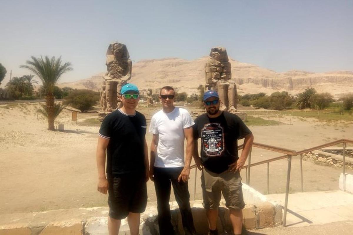 três homens estão em pé em frente a uma estátua