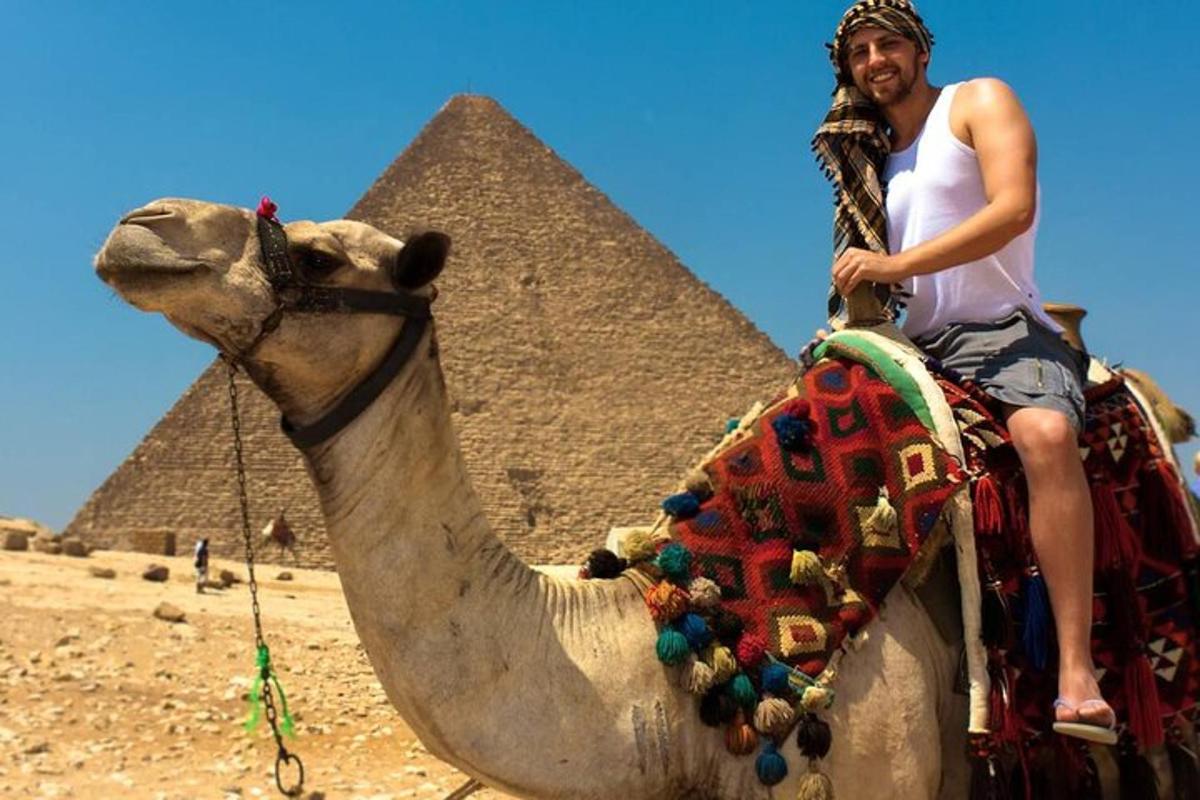 muž jedoucí na velbloudovi poblíž pyramid