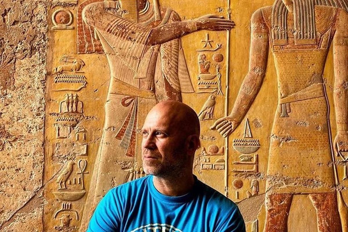 um homem sentado em frente a uma parede com uma estátua