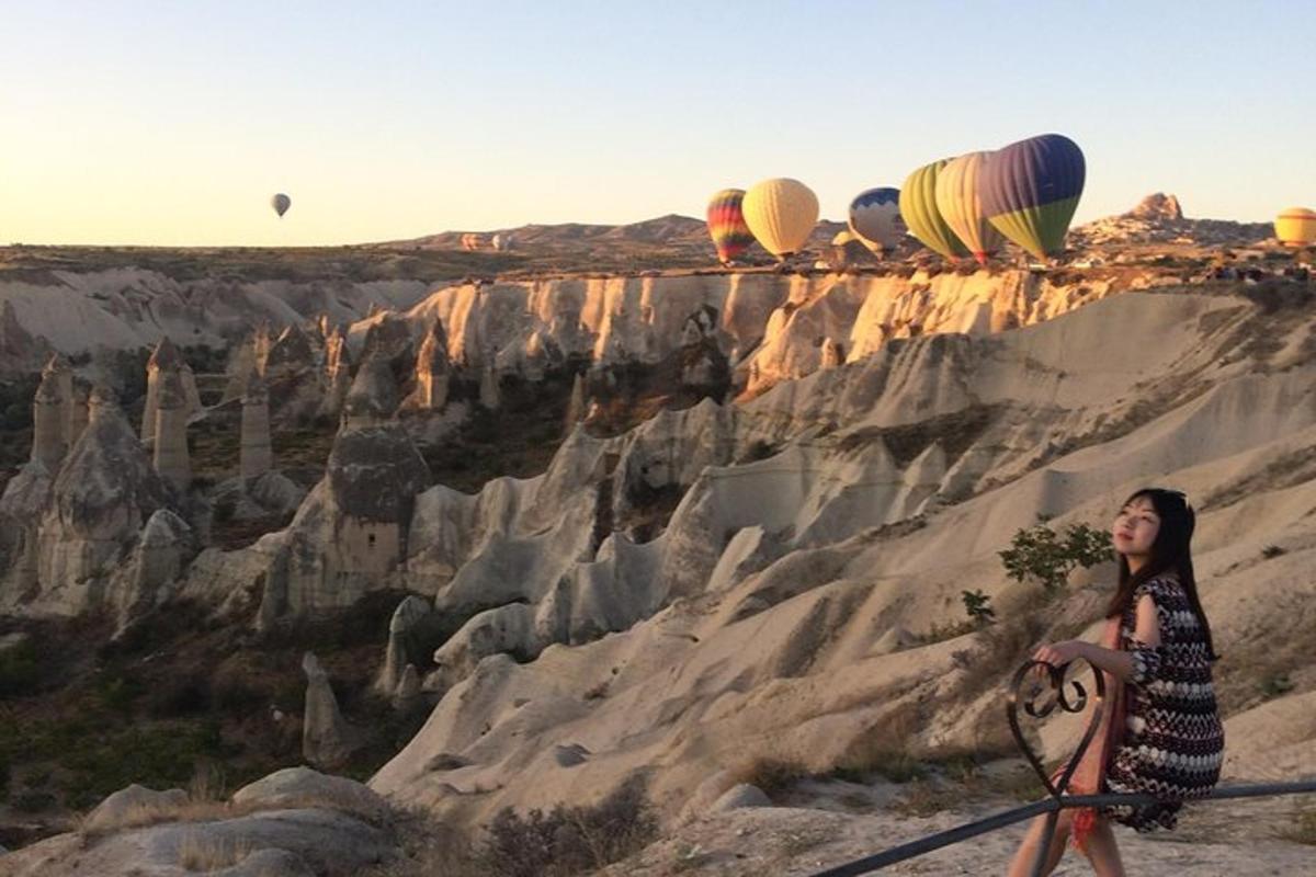 a woman standing next to a mountain with hot air balloons