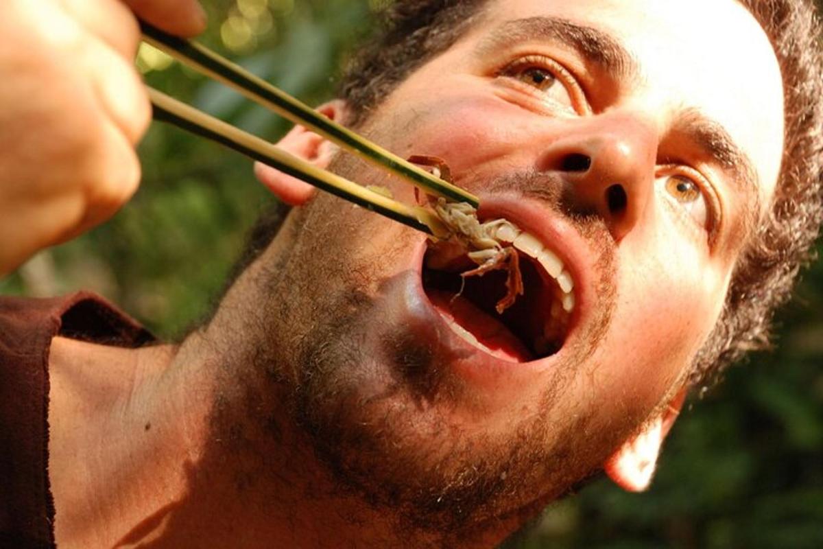a man eating food with chopsticks in his mouth