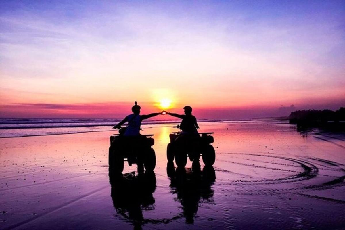 duas pessoas andando a cavalo na praia ao pôr do sol