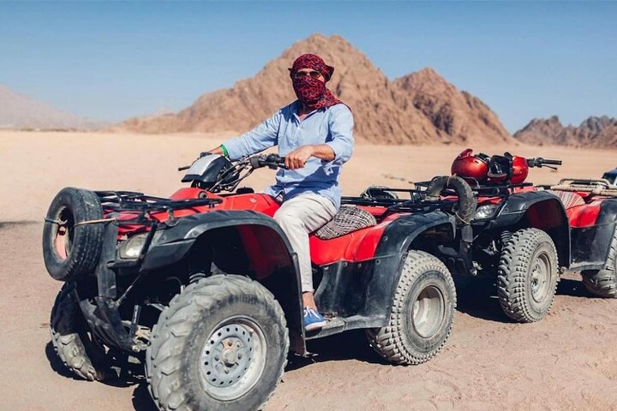 um homem sentado em um quadriciclo no deserto