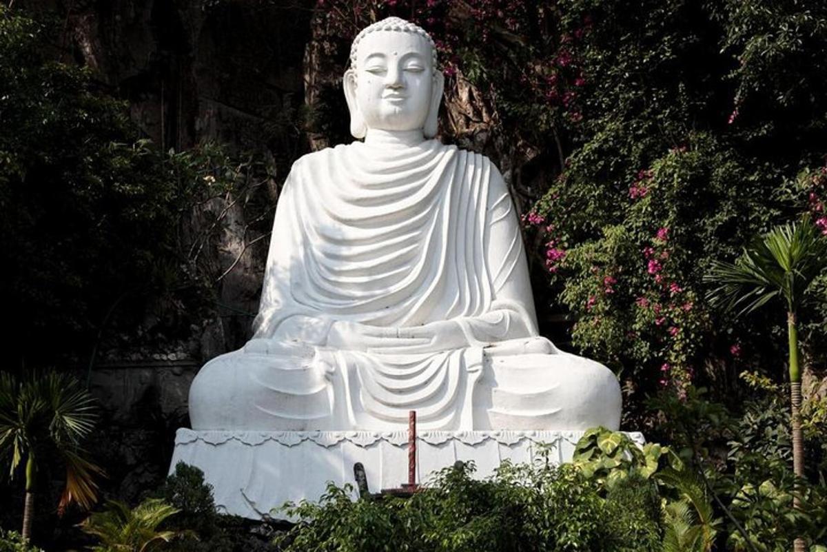 a large white statue sitting in a garden