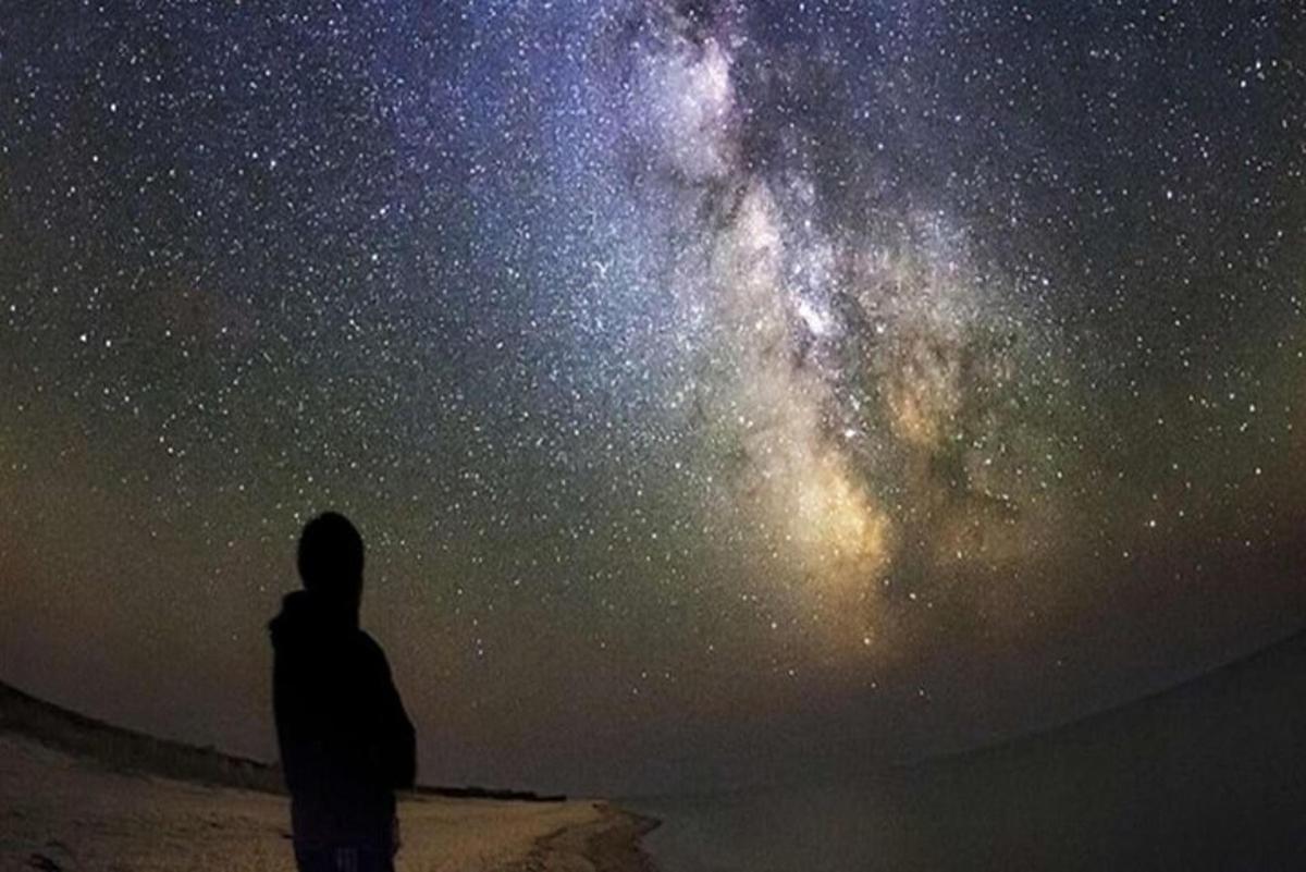 un uomo in piedi davanti a un cielo stellato
