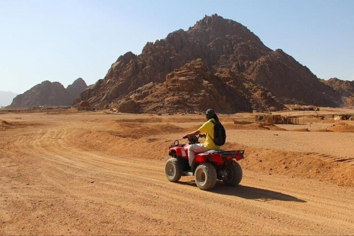 una persona que condueix un quad al desert