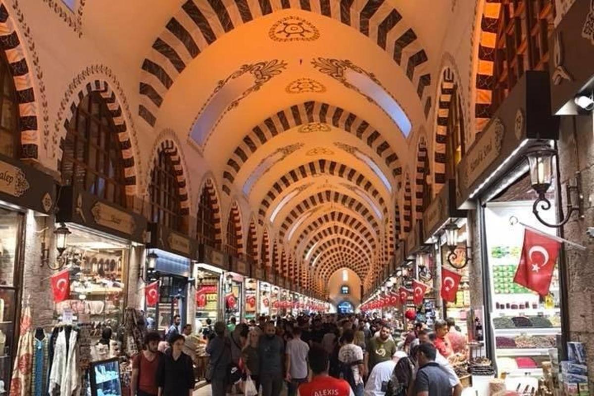 Una multitud de personas caminando por un mercado con techos abovedados.