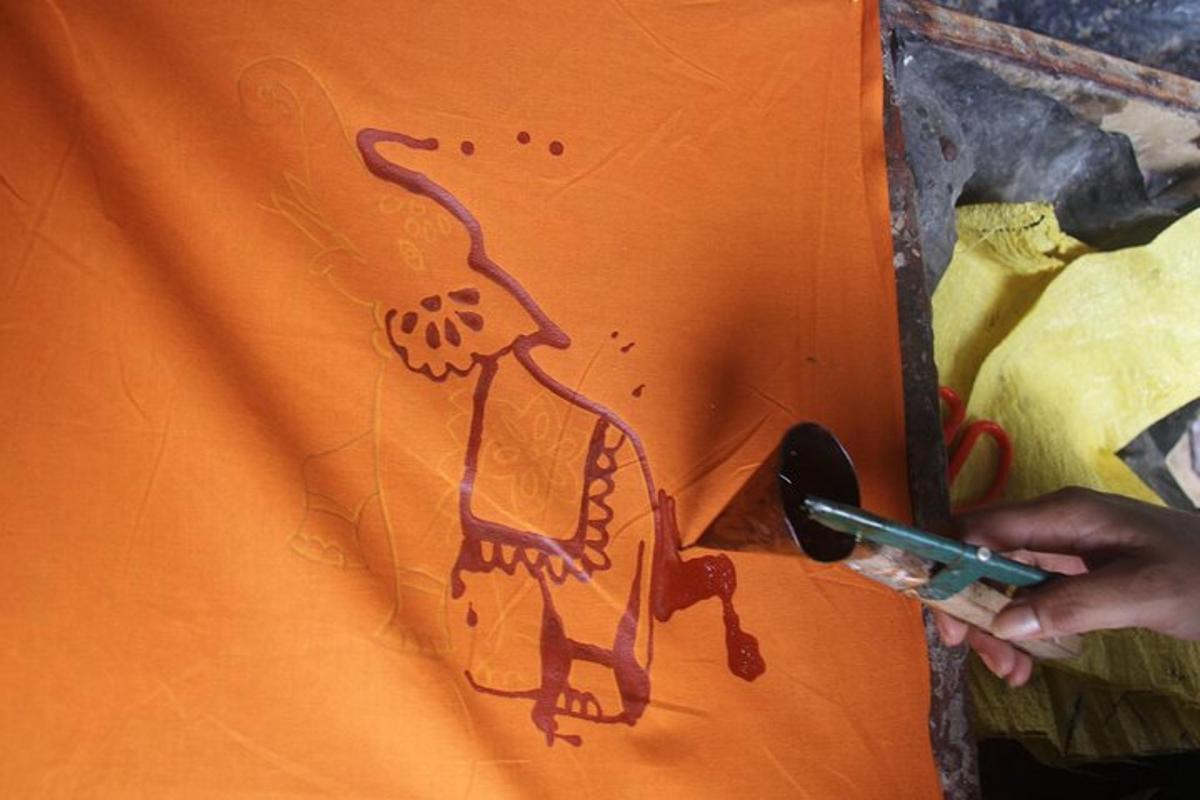 a person painting a picture of a dinosaur on an orange shirt