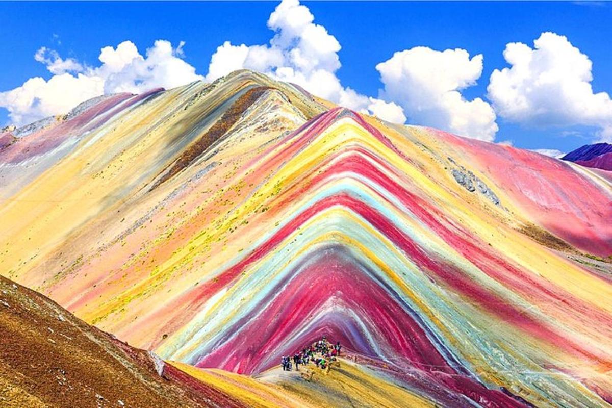 una montagna color arcobaleno con cielo azzurro e nuvole