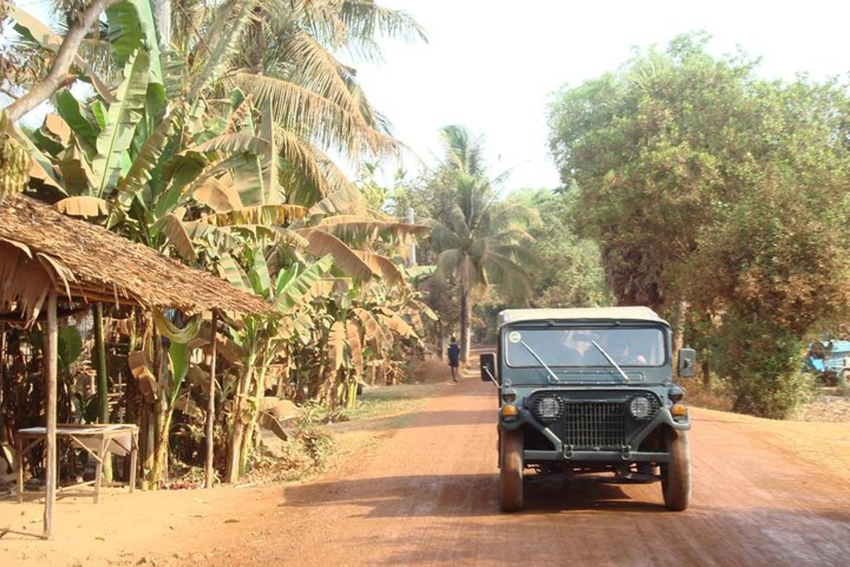 um jipe velho dirigindo por uma estrada de terra