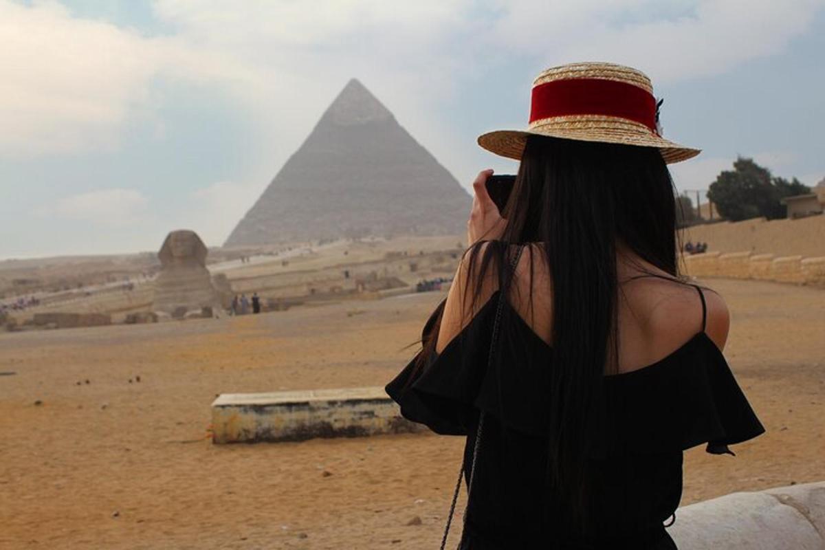 una donna con un cappello che scatta una foto delle piramidi