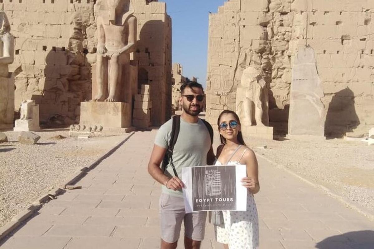 Un hombre y una mujer sosteniendo un cartel frente al templo.