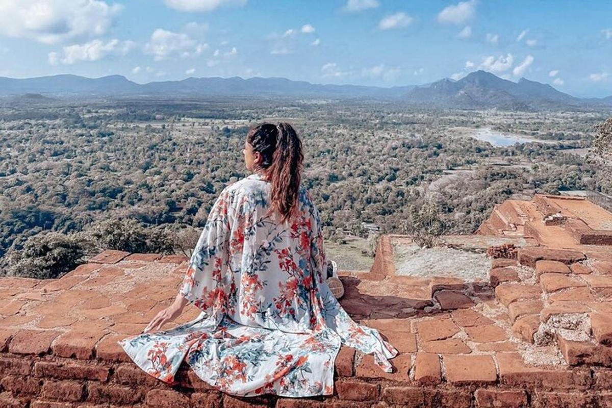uma mulher sentada na beira de um muro de tijolos