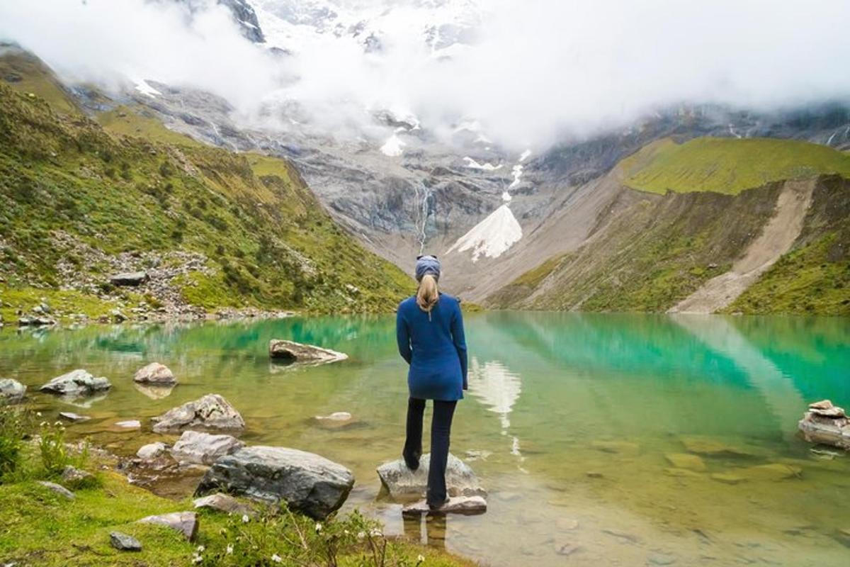 una donna in piedi su una roccia di fronte a un lago