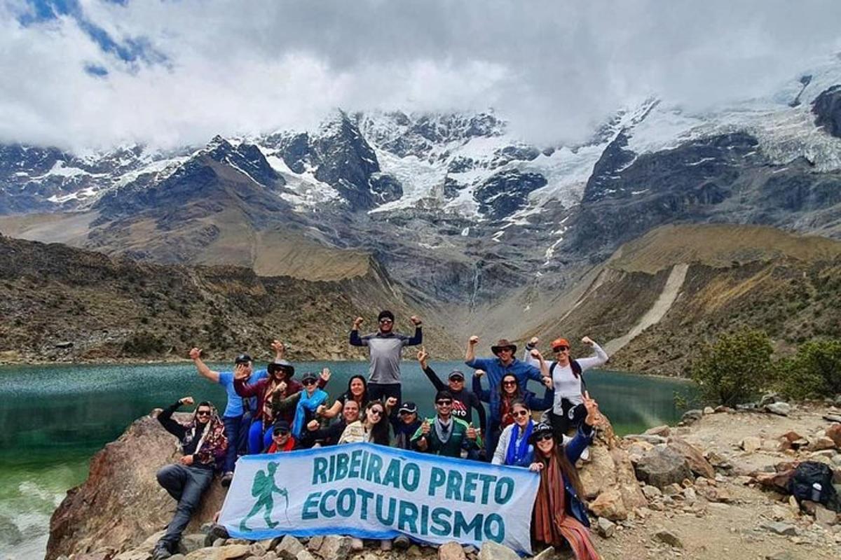 un gruppo di persone in piedi su una montagna con un cartello
