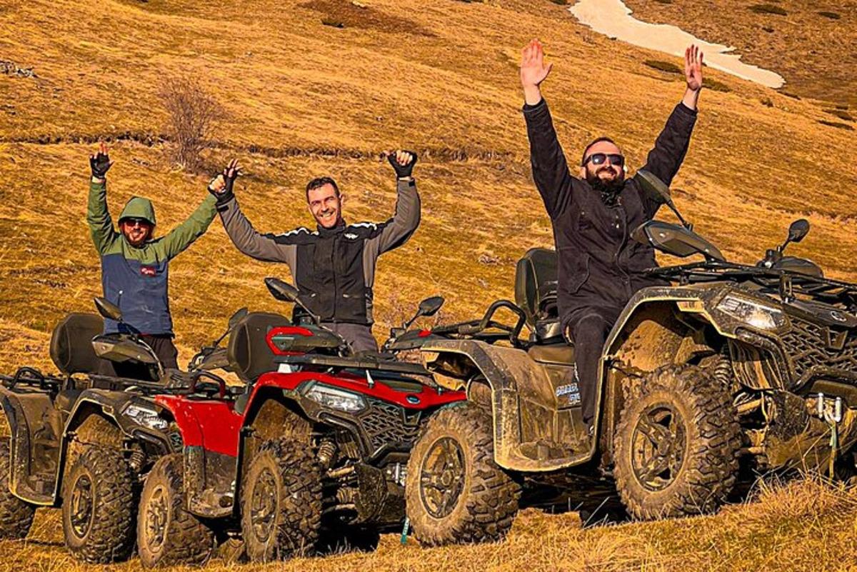 Három férfi ül ATV-ken, kezük a levegőbe emelve