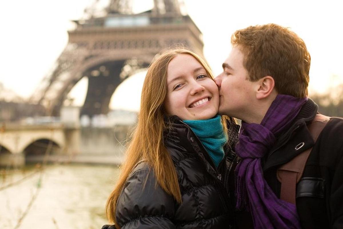a young couple kissing in front of the eiffel tower