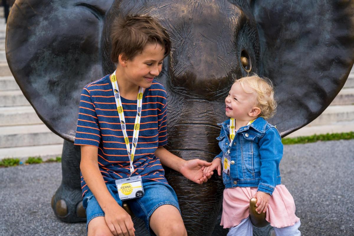 Un niño y una niña de pie junto a un elefante.