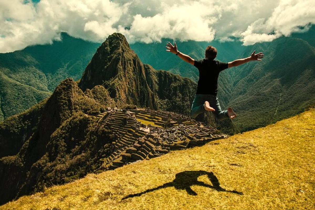 Un hombre parado en la cima de una montaña con los brazos extendidos.