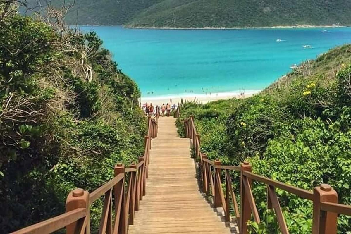 a wooden path leading to a beach with people on it