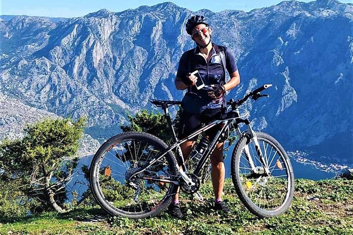 muž stojící vedle kola na hoře