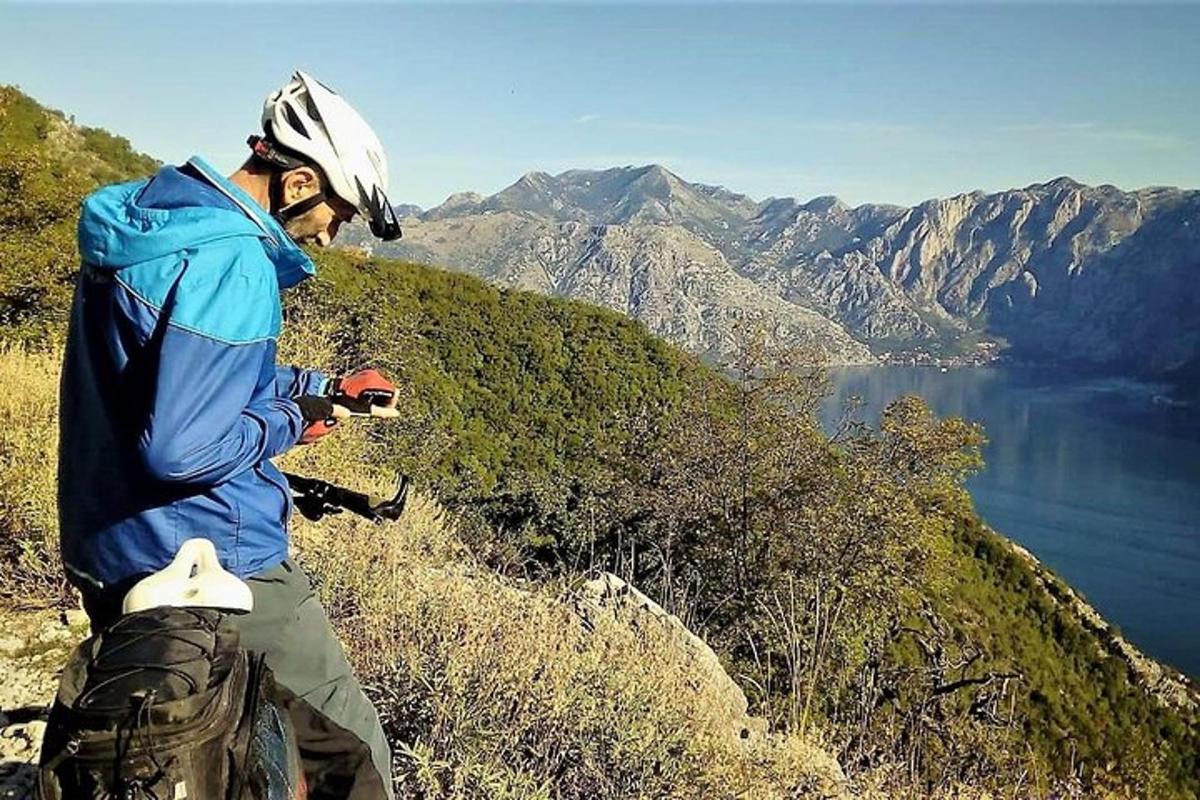 Un hombre parado en la cima de una montaña con vista a un lago.