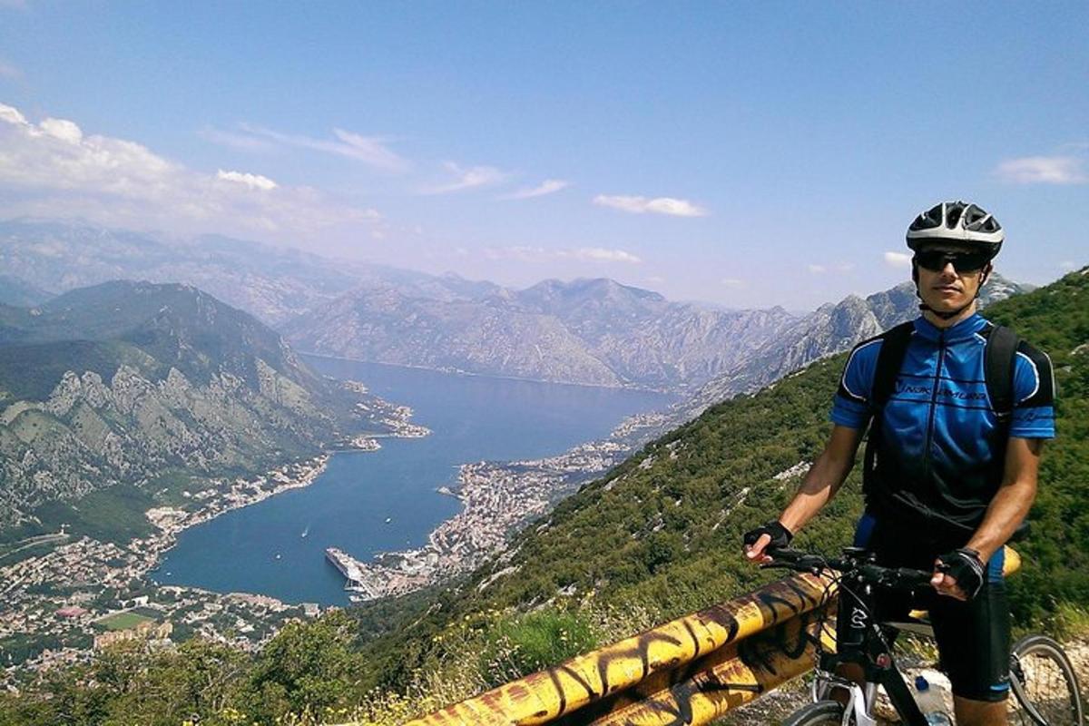 Ένας άντρας που στέκεται πάνω σε ένα ποδήλατο στην κορυφή ενός βουνού