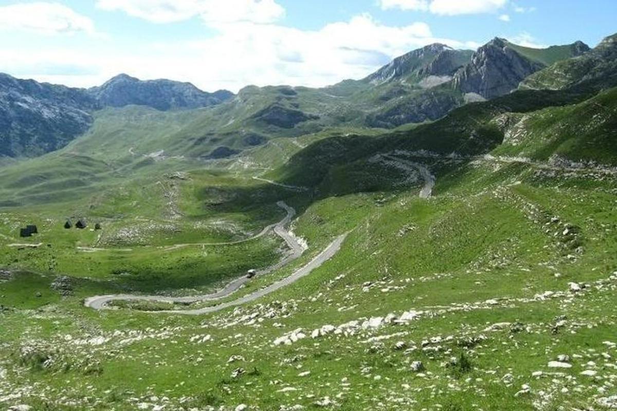 a green hillside with a winding road on a mountain