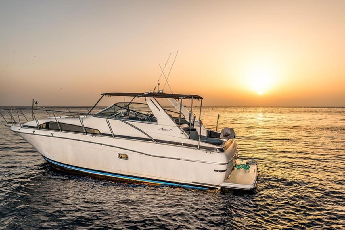 a white boat in the water at sunset