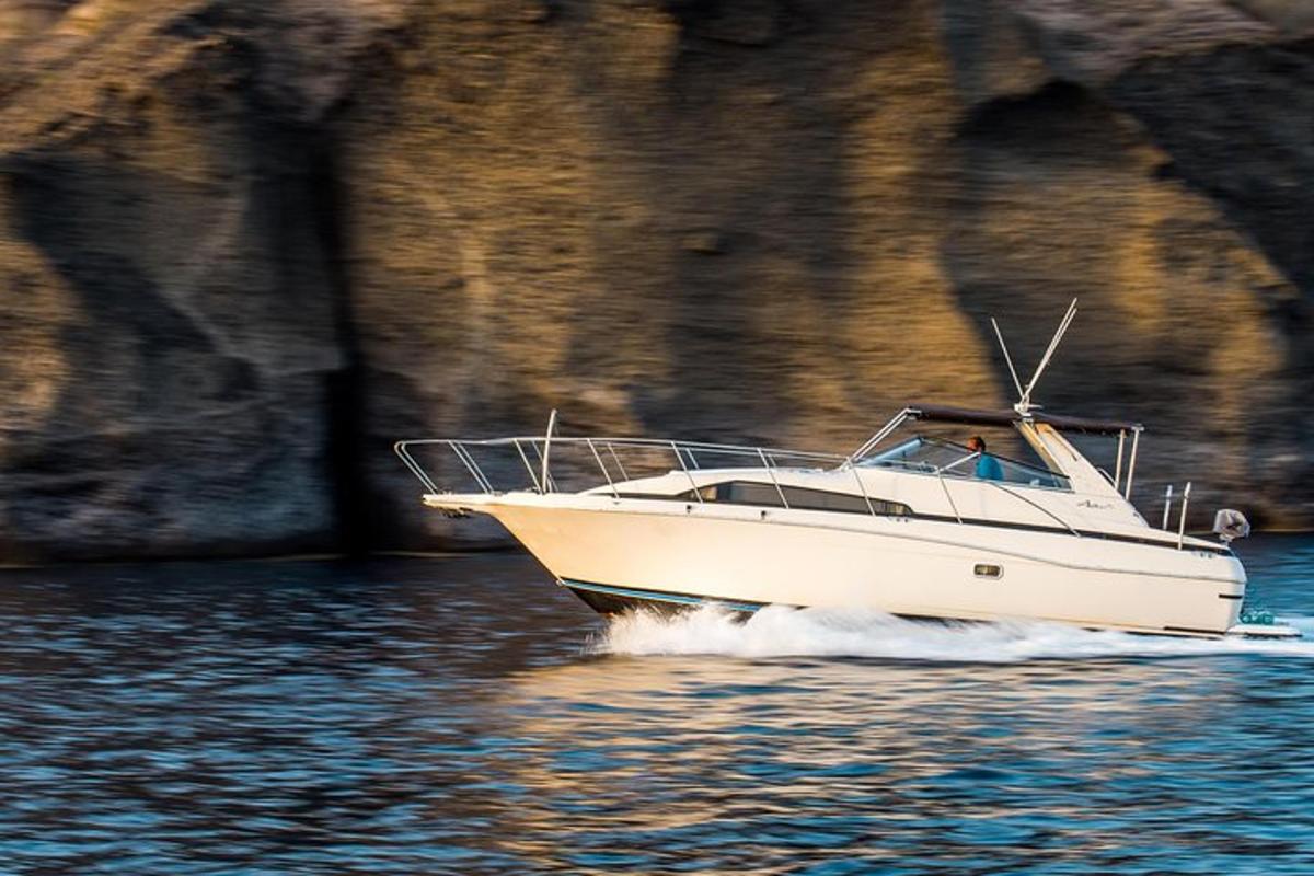 a white boat in the water near a cliff