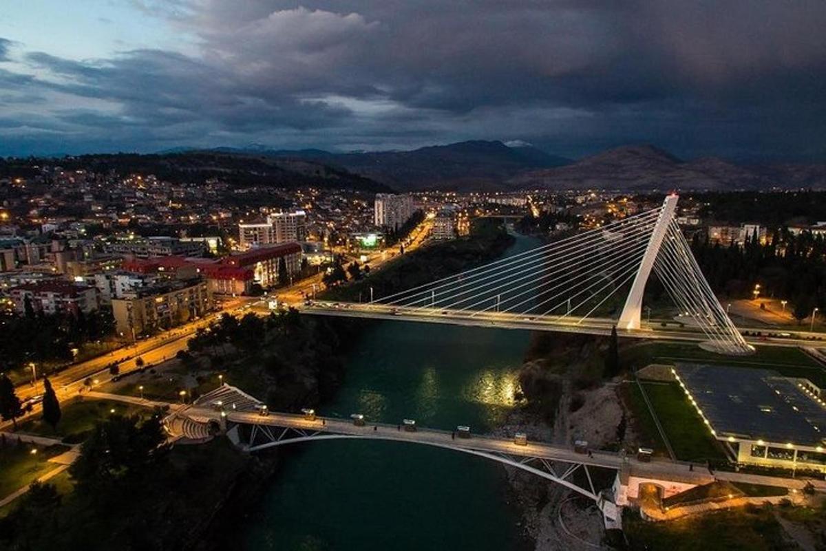 Μια γέφυρα πάνω από ένα ποτάμι με μια πόλη τη νύχτα